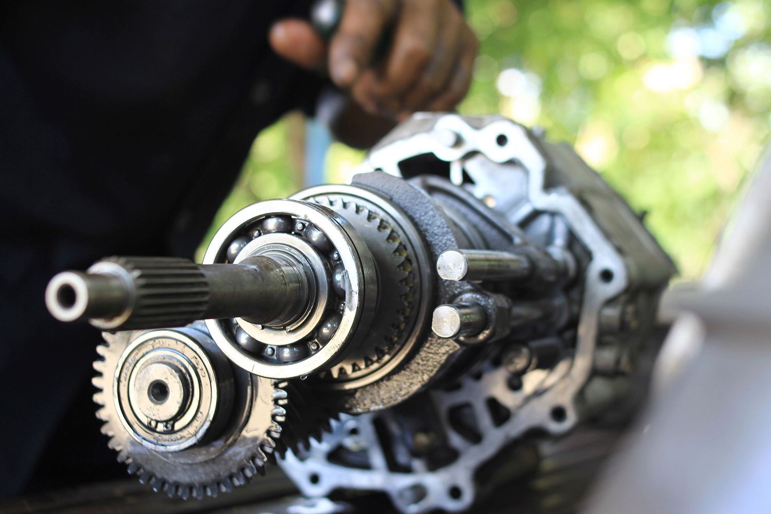 A close-up of a hand of a car mechanic, fixing disassembled gear parts.
