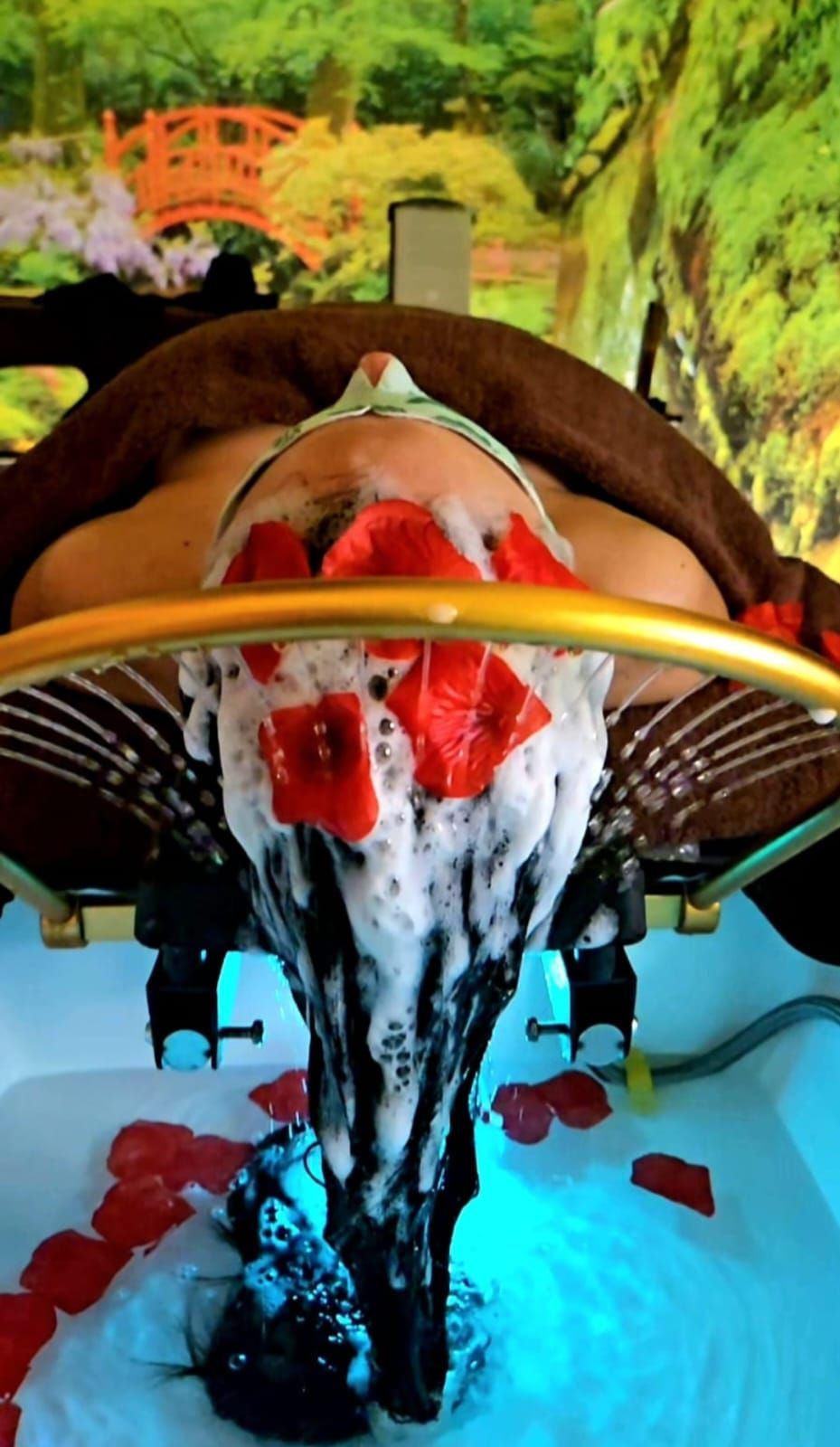 Sala spa con proiezione di scene di giardini giapponesi. Lettini per massaggi, pavimento in legno, luci soffuse.