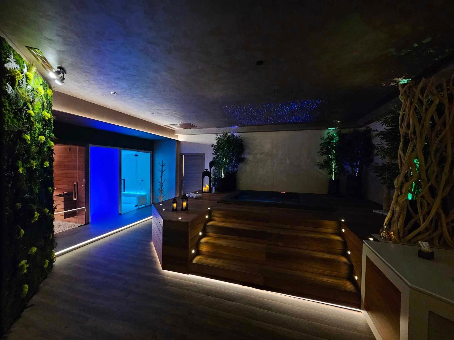 Esposizione di un negozio di abbigliamento con jeans impilati su scaffali illuminati e fiori. Sullo sfondo, appendiabiti.