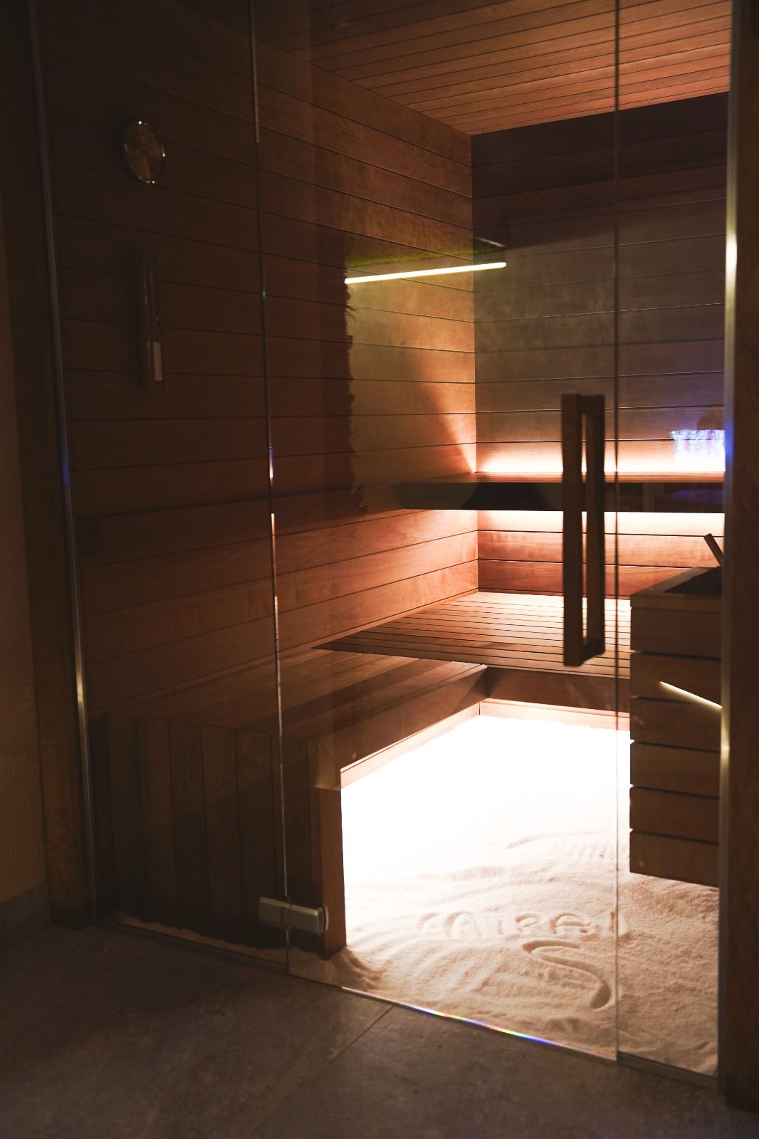 Tavolo espositivo per gioielli in un negozio di abbigliamento, con teche in vetro su gambe bianche decorate. Abiti su rastrelliere tutt'intorno.