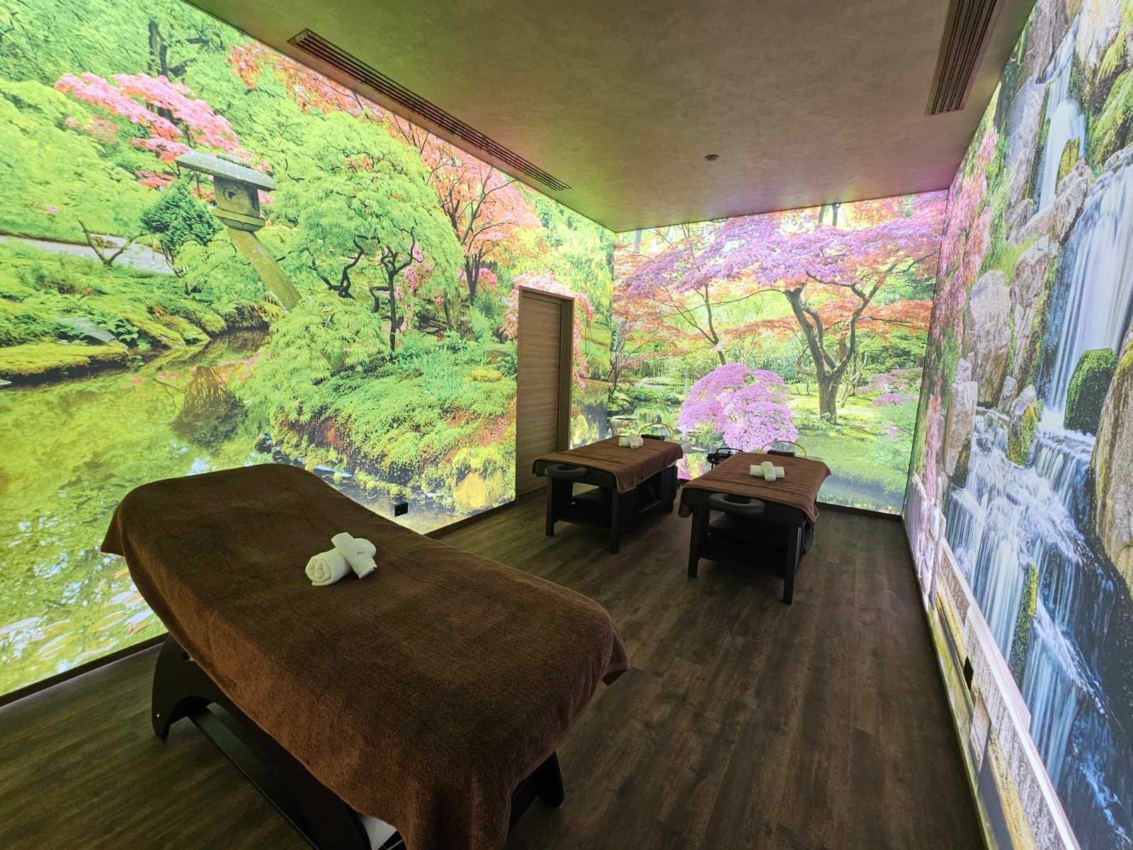 Sala benessere con lettini per massaggi; scene naturali proiettate sulle pareti.