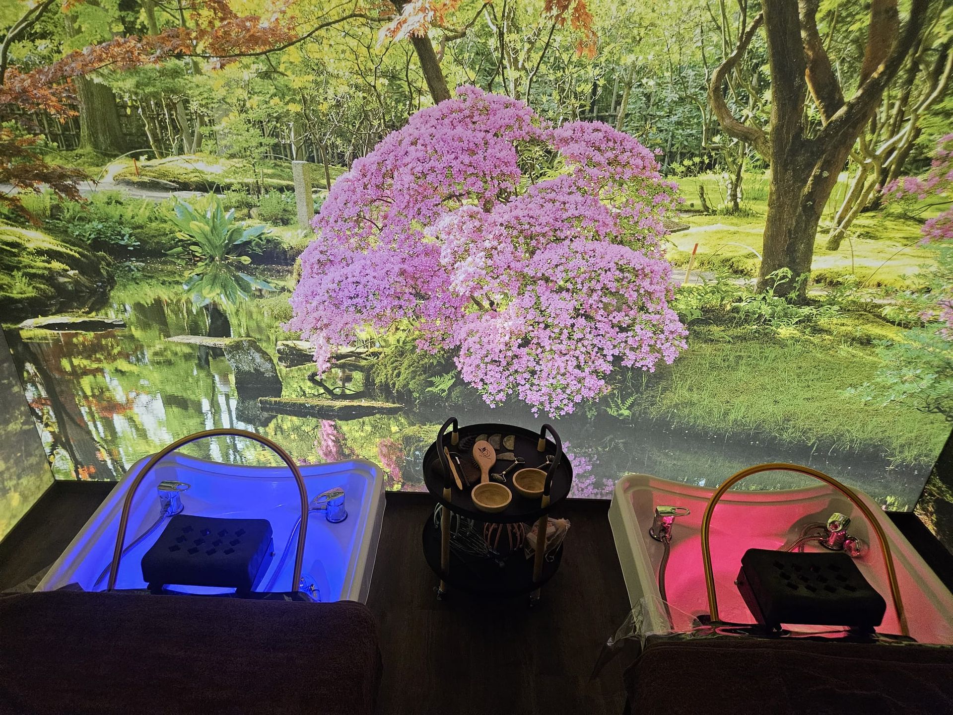 Due vasche per pediluvio con bordi luminosi, servizio da tè centrale e sfondo di un giardino giapponese.