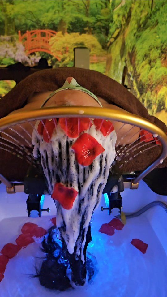 Opera d'arte in schiuma bianca con petali rossi e uno sfondo raffigurante una scena di giardino.