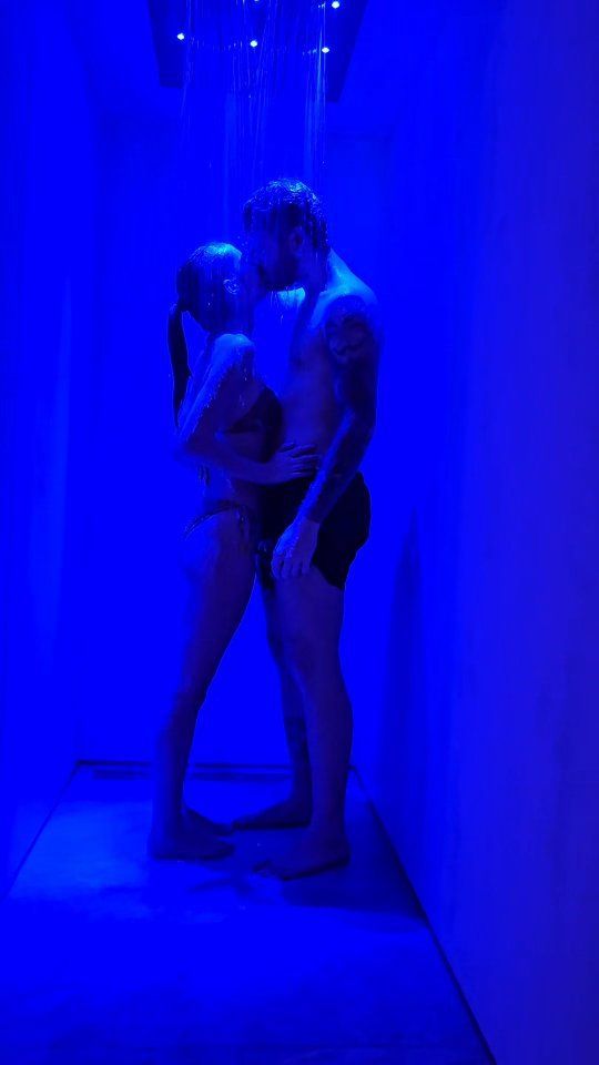 Tavolo espositivo per gioielli in un negozio di abbigliamento, con teche in vetro su gambe bianche decorate. Abiti su rastrelliere tutt'intorno.