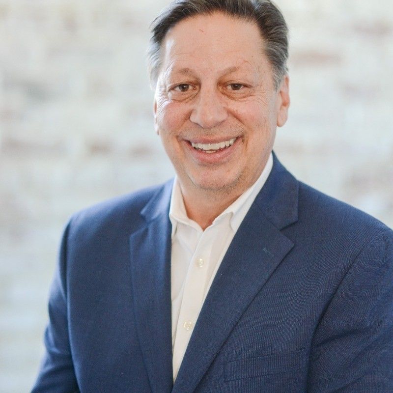 A man in a blue suit and white shirt is smiling for the camera.