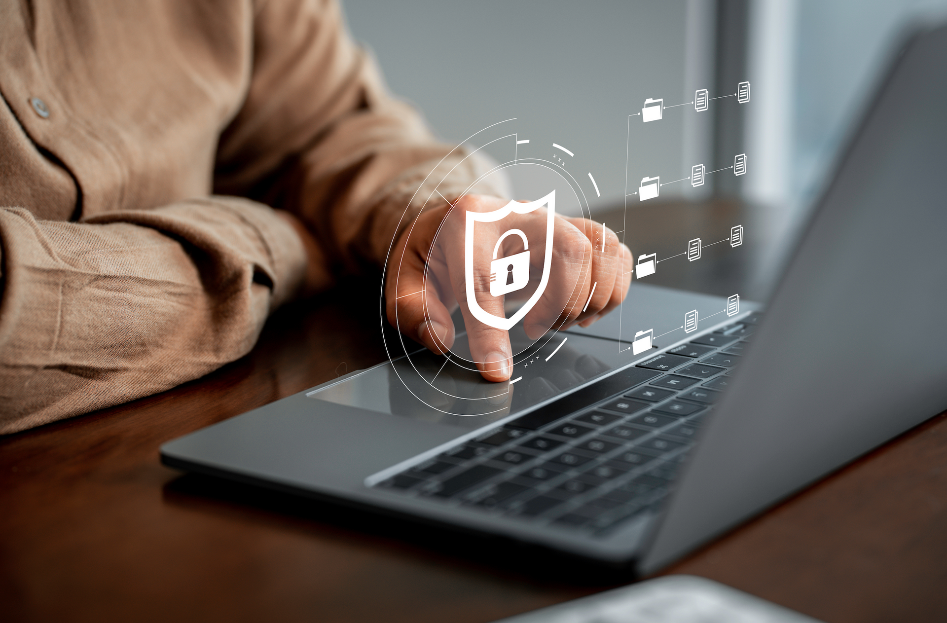 A person is using a laptop computer with a shield icon on the screen.