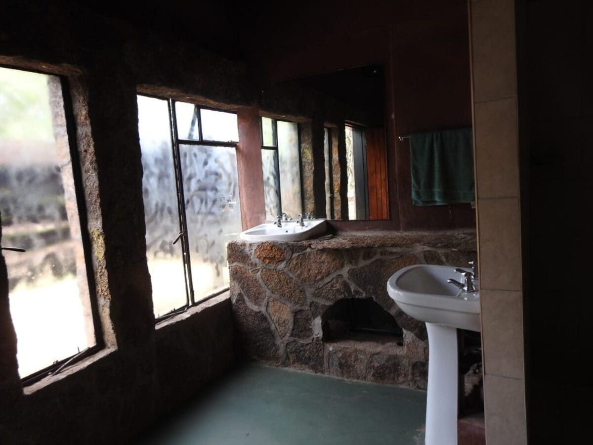 Bathroom with stone walls, a large window, and a pedestal sink.