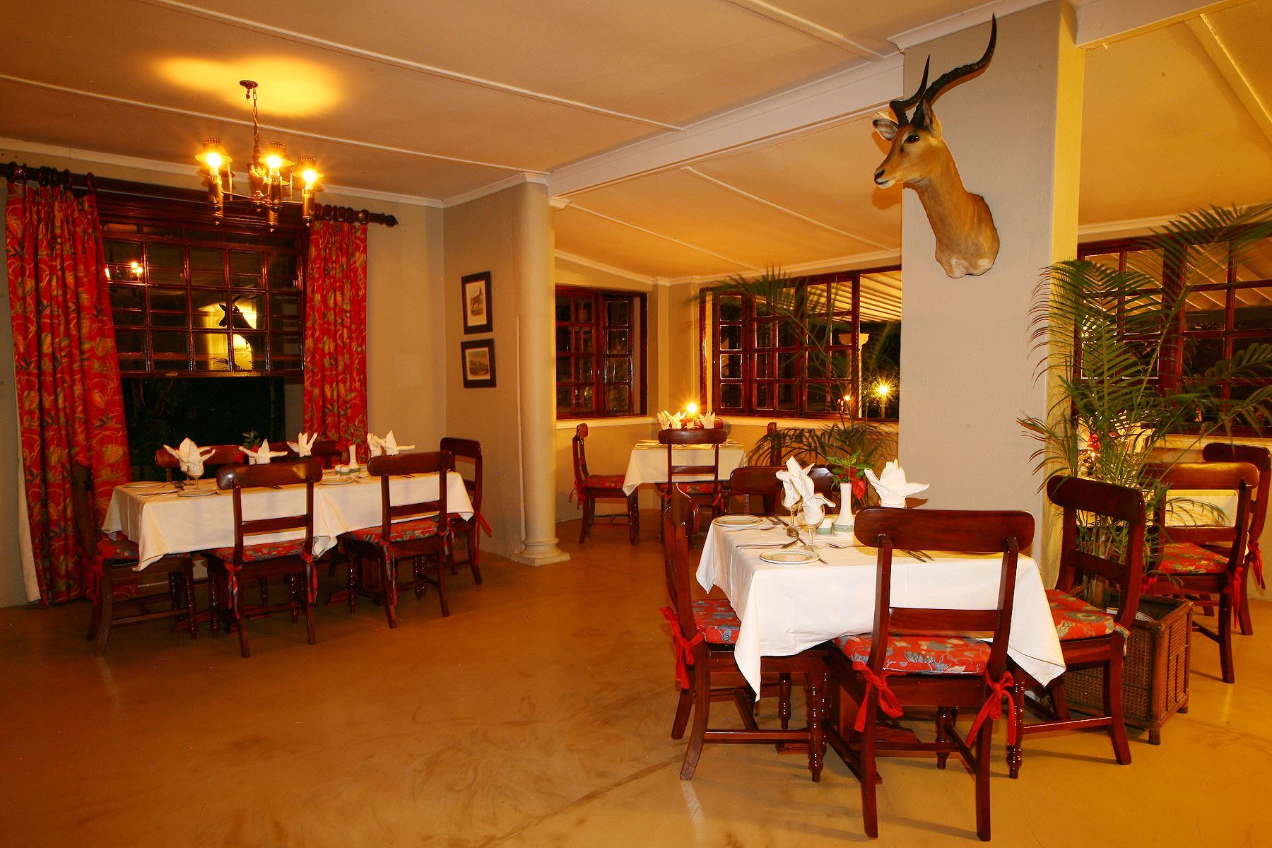Bedroom with a four-poster bed draped in mosquito netting, thatched roof, and wooden furnishings.