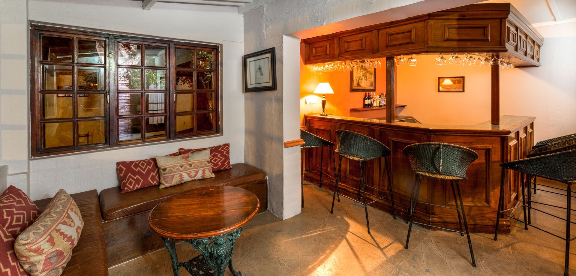 Two twin beds with white linens, mosquito netting, wooden headboard, and a window in a bright room.