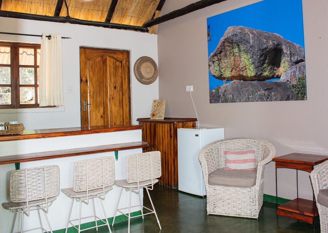 Interior of a room with a bar, wicker chairs, and a landscape photo.