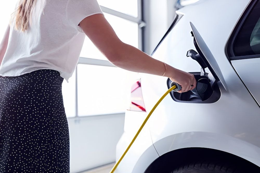 A Woman Is Charging Her Electric Car In A Garage — In-Line Electrical Southern Highlands in Carrick, NSW