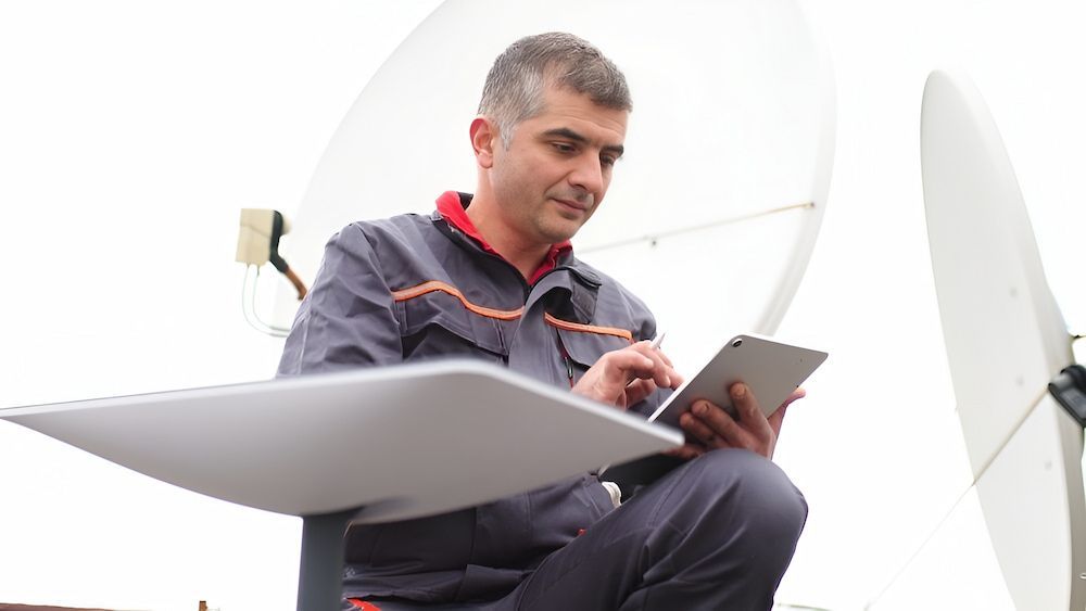 A Man Is Sitting On The Ground Using A Tablet Computer — In-Line Electrical Southern Highlands in Bowral, NSW