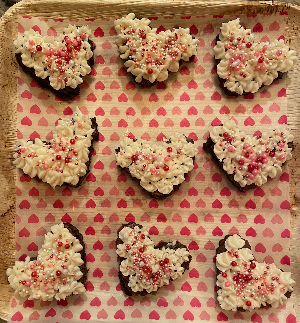 A tray of chocolate hearts covered in frosting and sprinkles