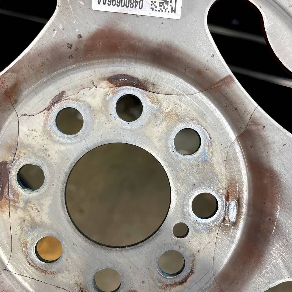 Cracked aluminum car wheel with multiple cracks radiating from the center. | Frontline Auto Repair