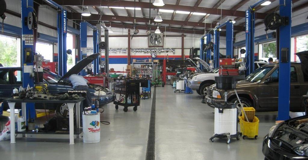 Interior of an auto repair shop with several cars on lifts, tools, and equipment. | Frontline Auto Repair