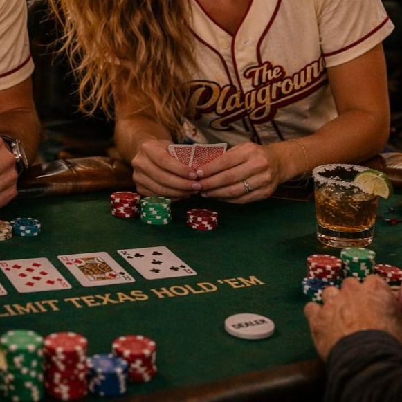 Poker players at a green felt Texas Hold’em table with chips, cards, and drinks