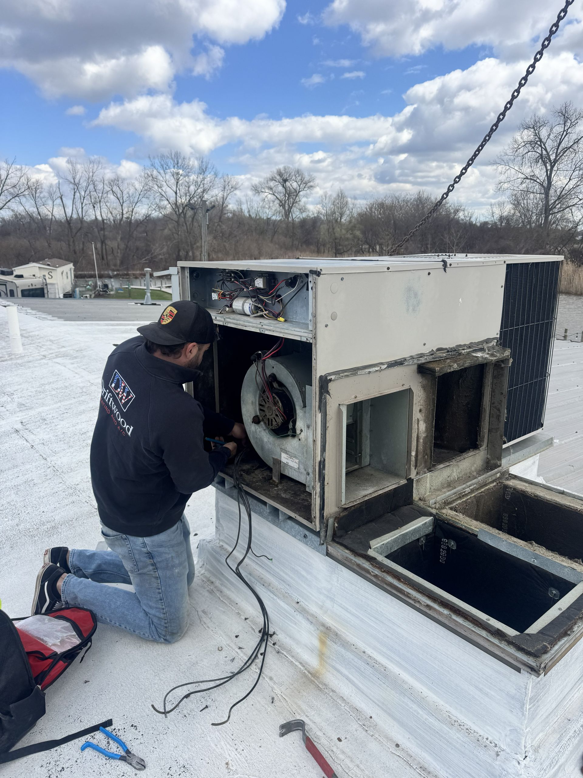 A vertical HVAC unit in a utility closet, with its access panel removed to reveal internal wiring.
