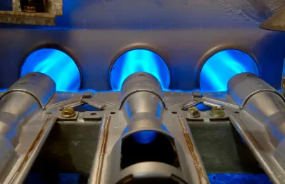 Close-up of gas furnace burners with steady, bright blue flames heating the interior chambers.