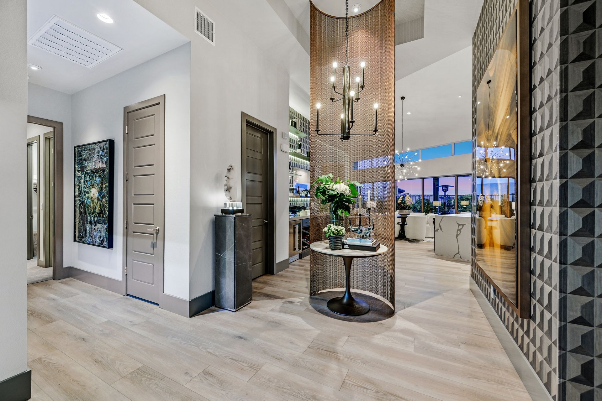 Elegant apartment hallway with ornate lighting, patterned walls, and hardwood flooring.