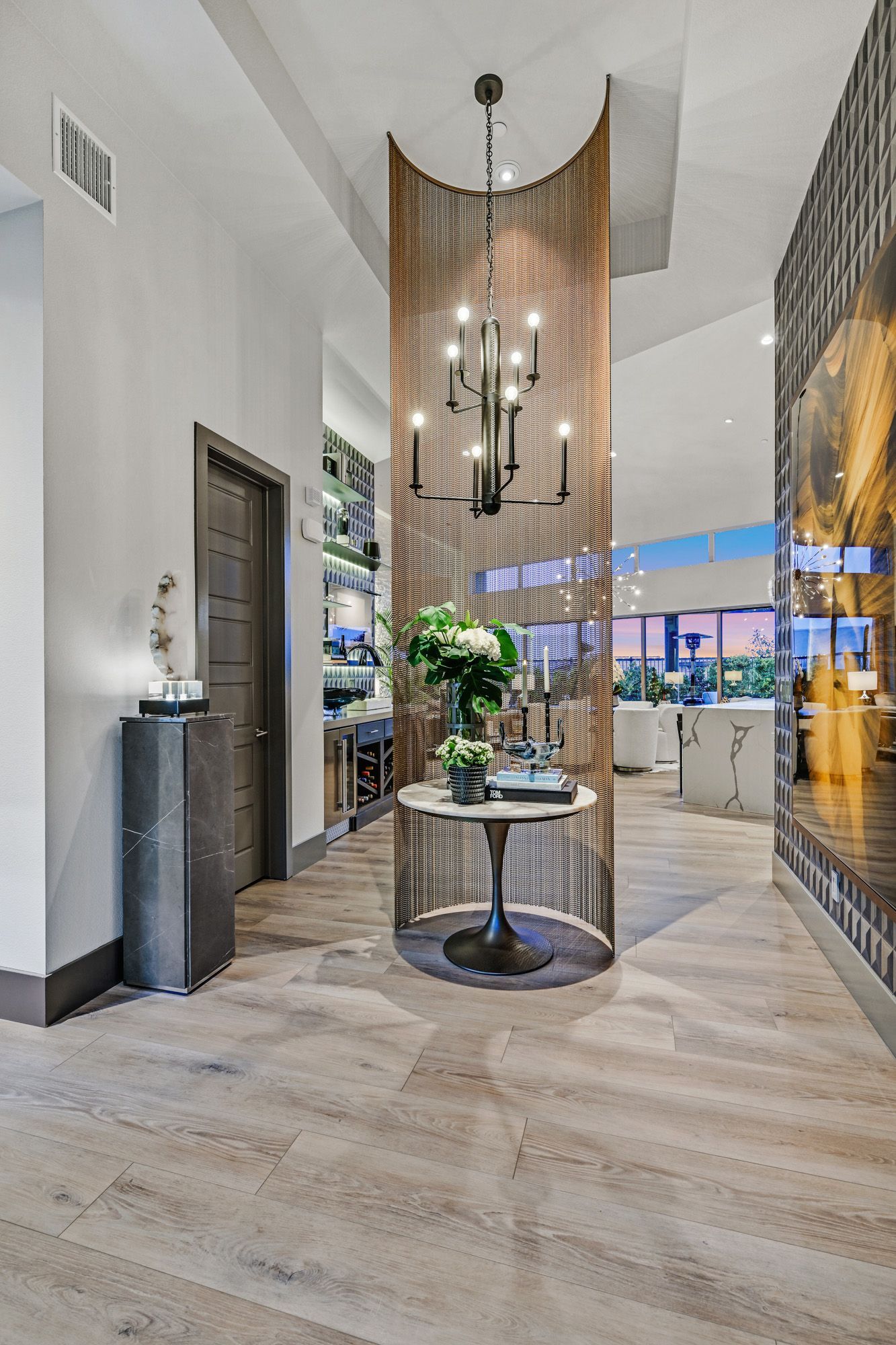 Elegant entryway with chandelier, circular table, and metallic curtain.
