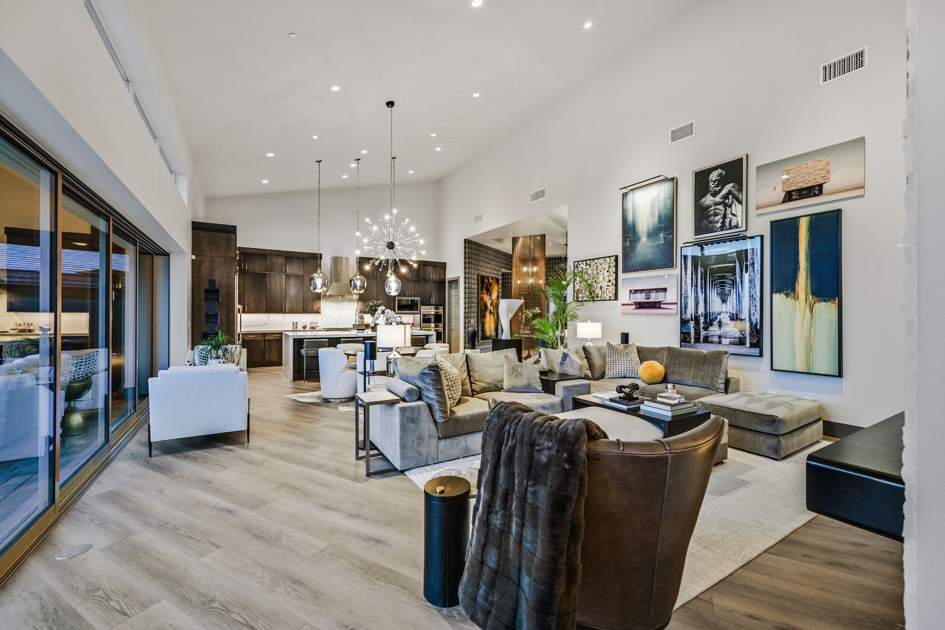 Spacious modern living room with open layout, hardwood floors, large windows, and art.