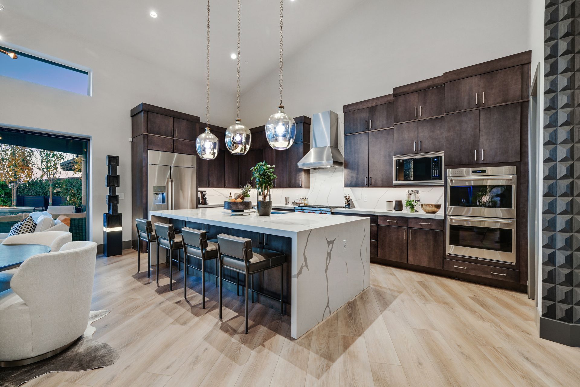 Modern kitchen with dark wood cabinets, large island, and stainless steel appliances.