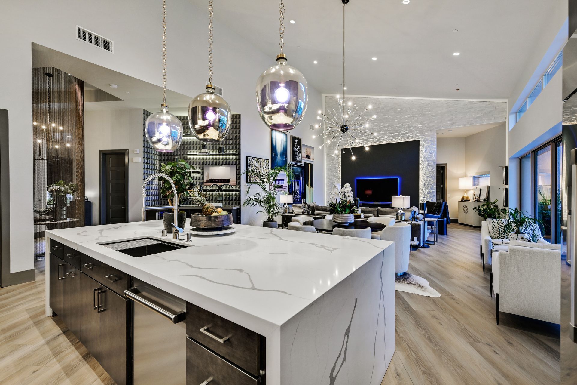 Modern kitchen with large island, pendant lights, wine rack, and open living area.
