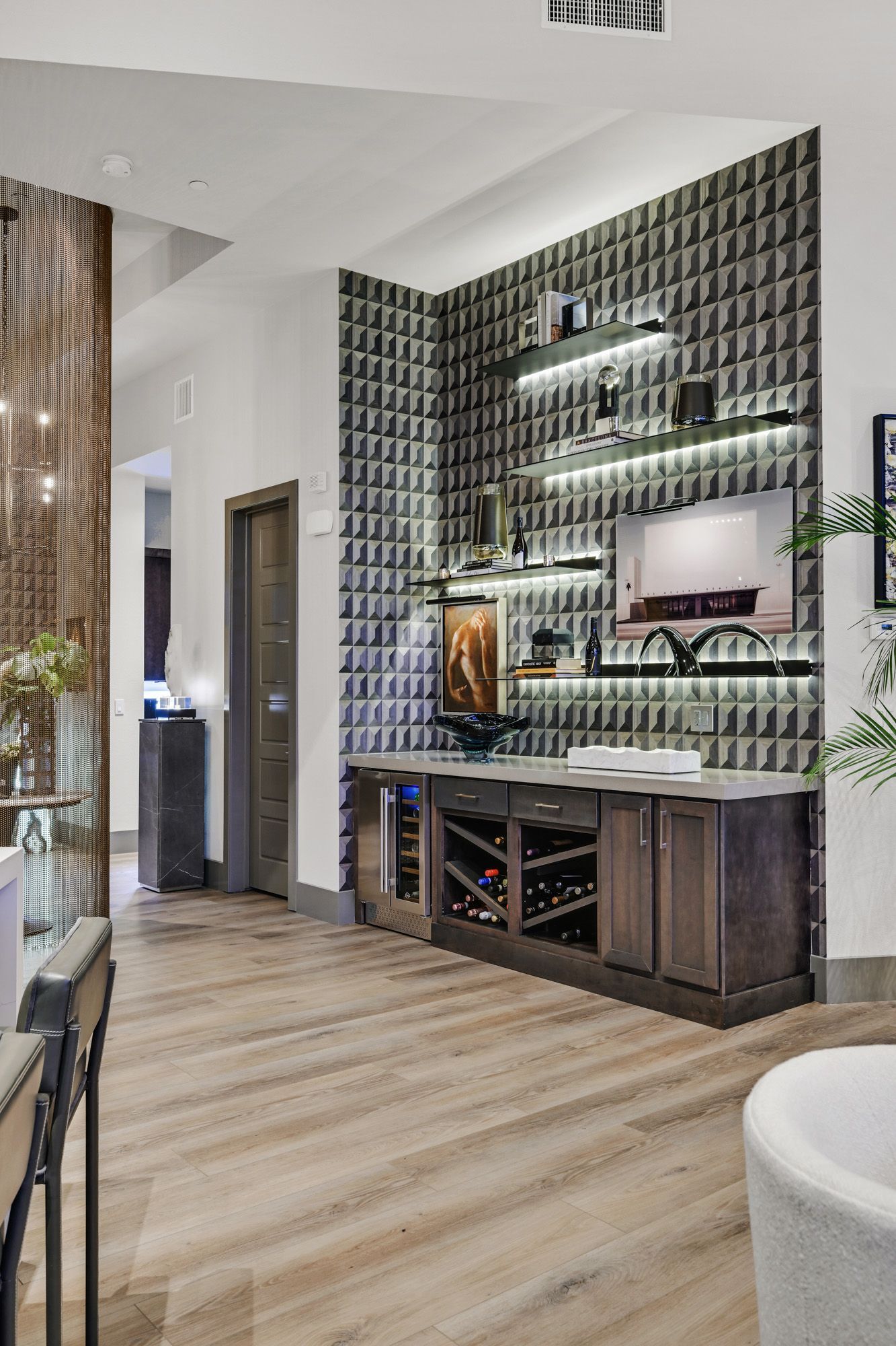 Bar area with wine storage, shelving, textured wall, and built-in TV.