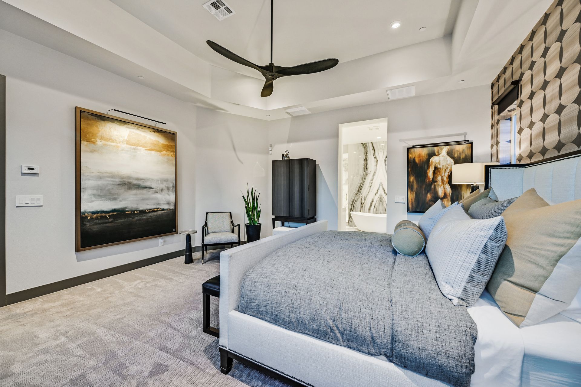 Upscale bedroom with bed, artwork, dark furniture, and patterned wall.