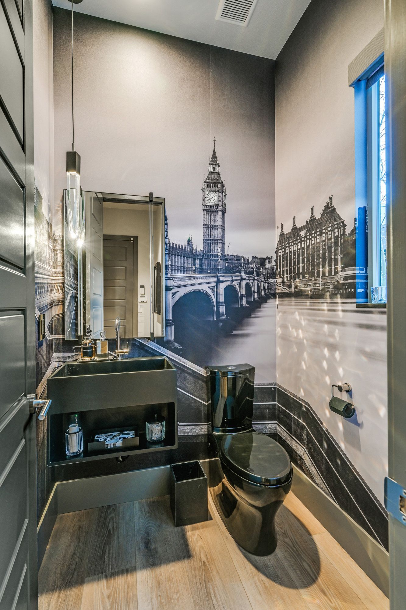Black-and-white-themed powder room with a London skyline mural behind a black toilet.