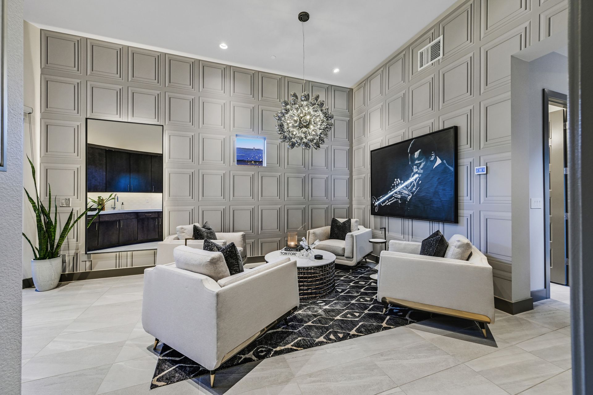 Elegant living room with white sofas, large TV, and gray paneled walls.