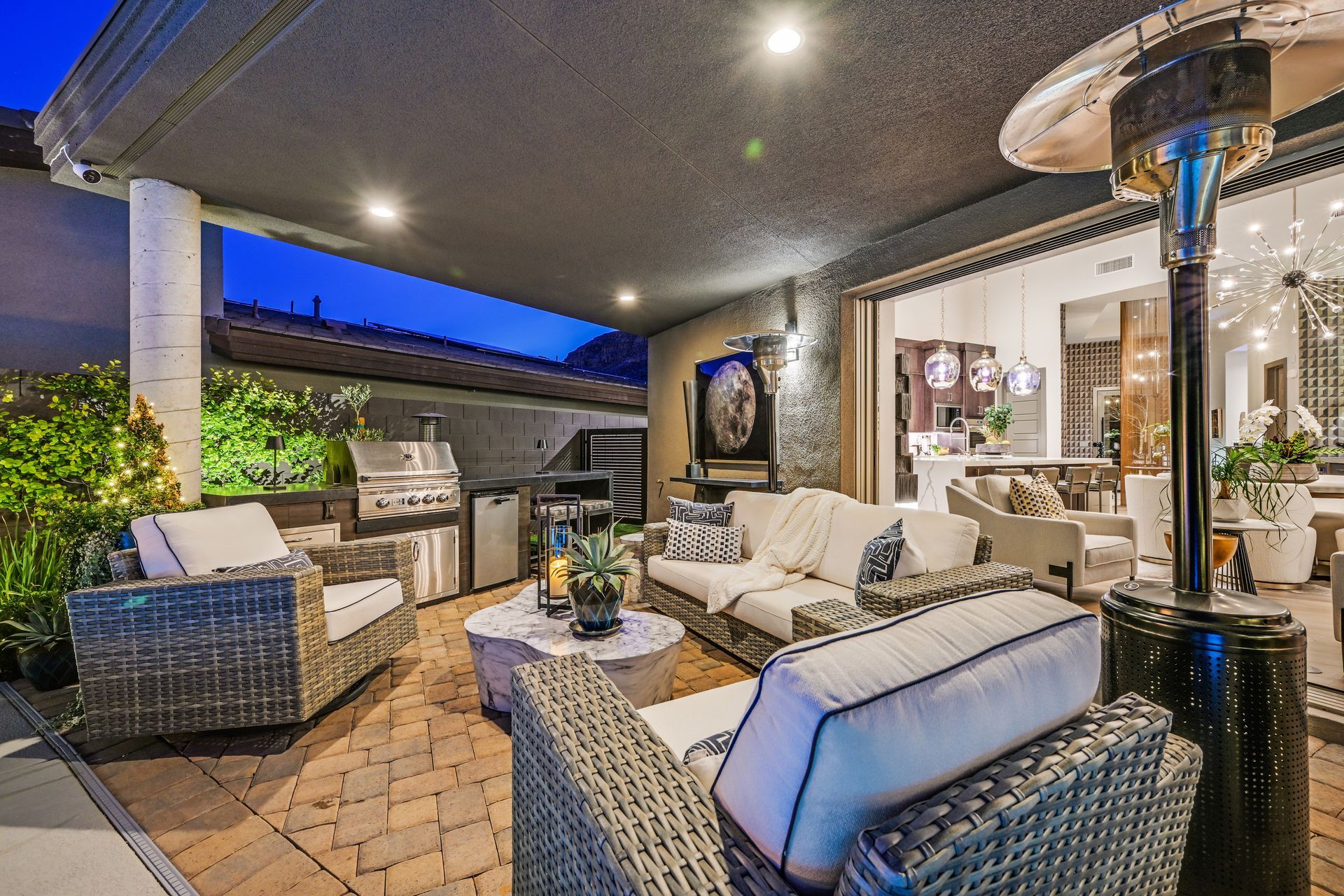 Patio with outdoor furniture, grill, and heater at dusk.