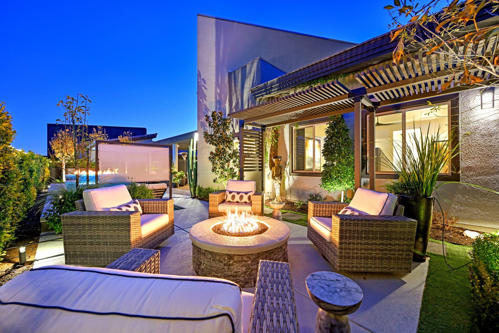 Outdoor patio with fire pit, seating, and a projector screen under a starry sky.