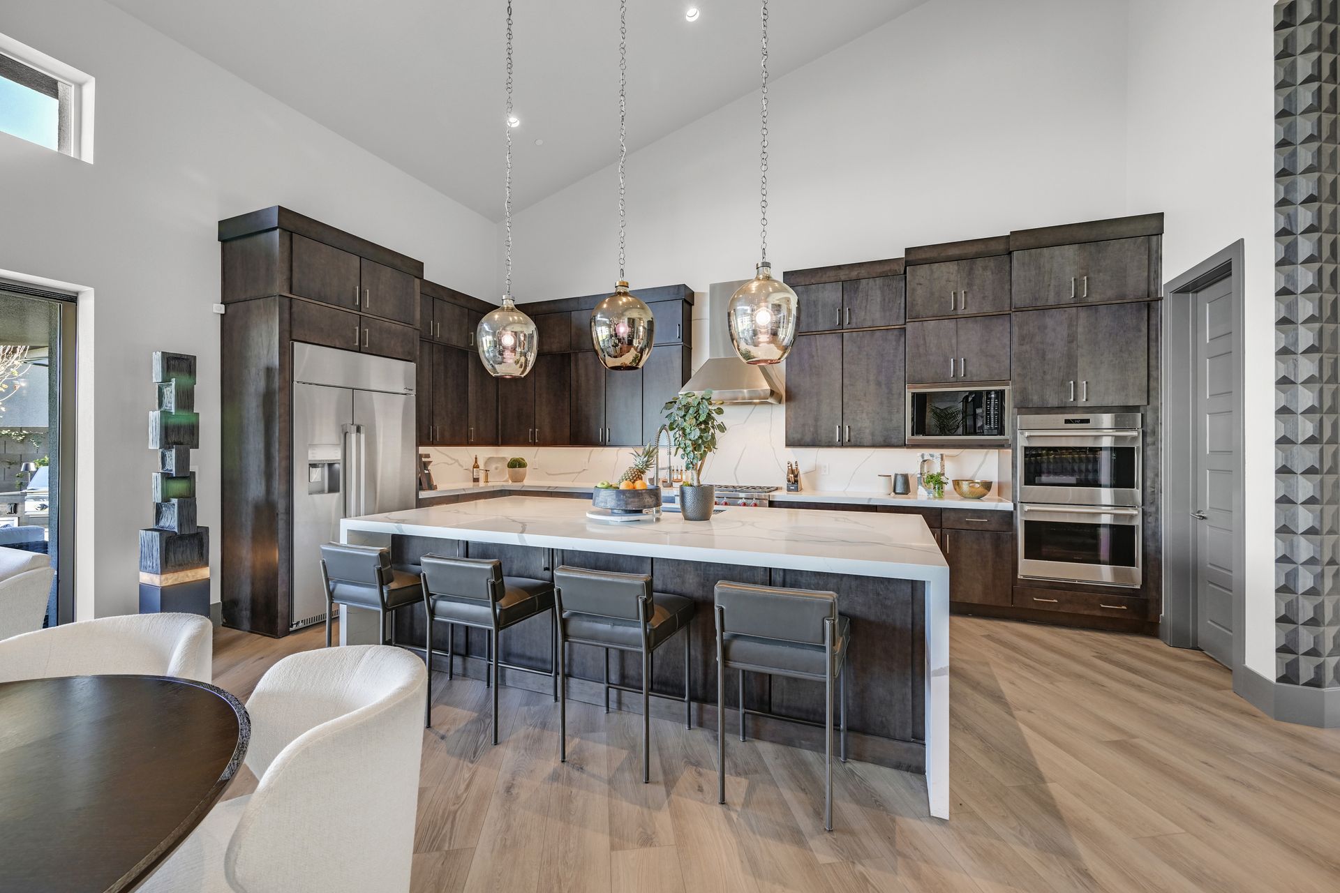 Modern kitchen with dark cabinetry, large island, and pendant lights.
