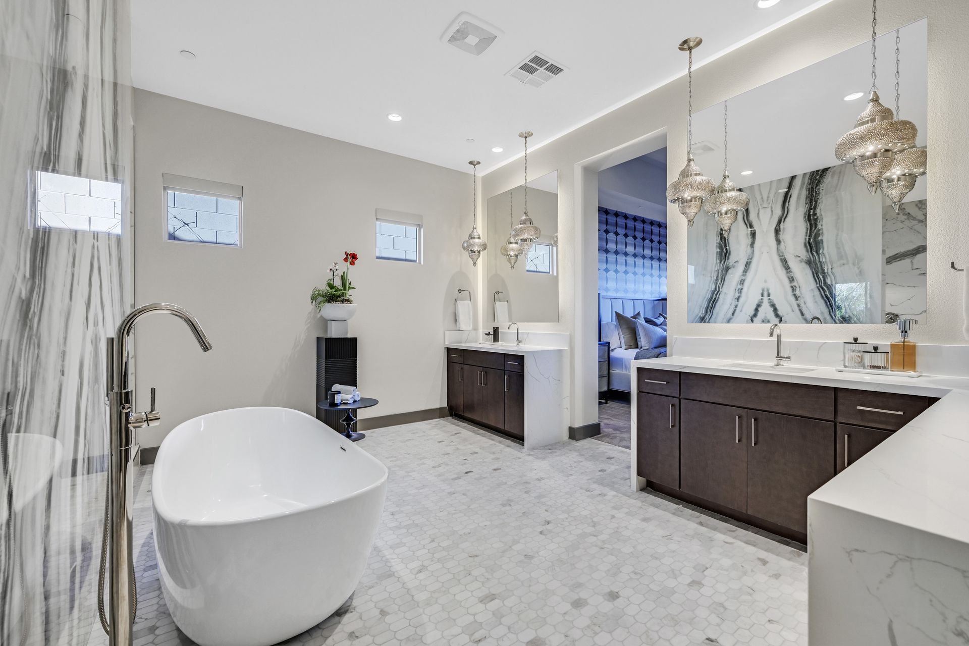 Luxurious bathroom with freestanding tub, marble walls, dual sinks, and ornate light fixtures.