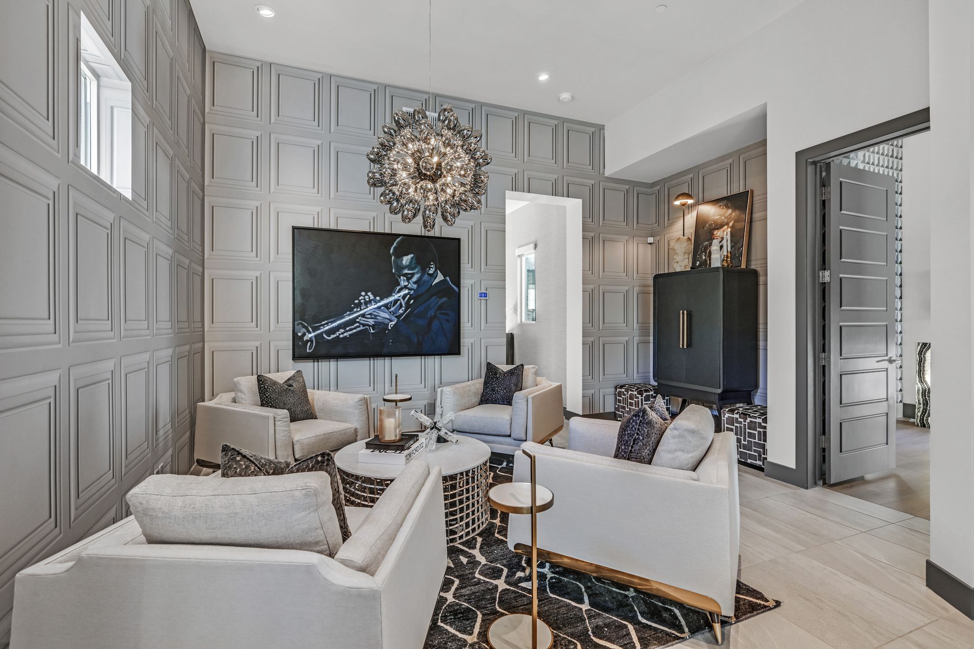 Living room with grey paneled walls, white sofas, black and white rug, and artwork.