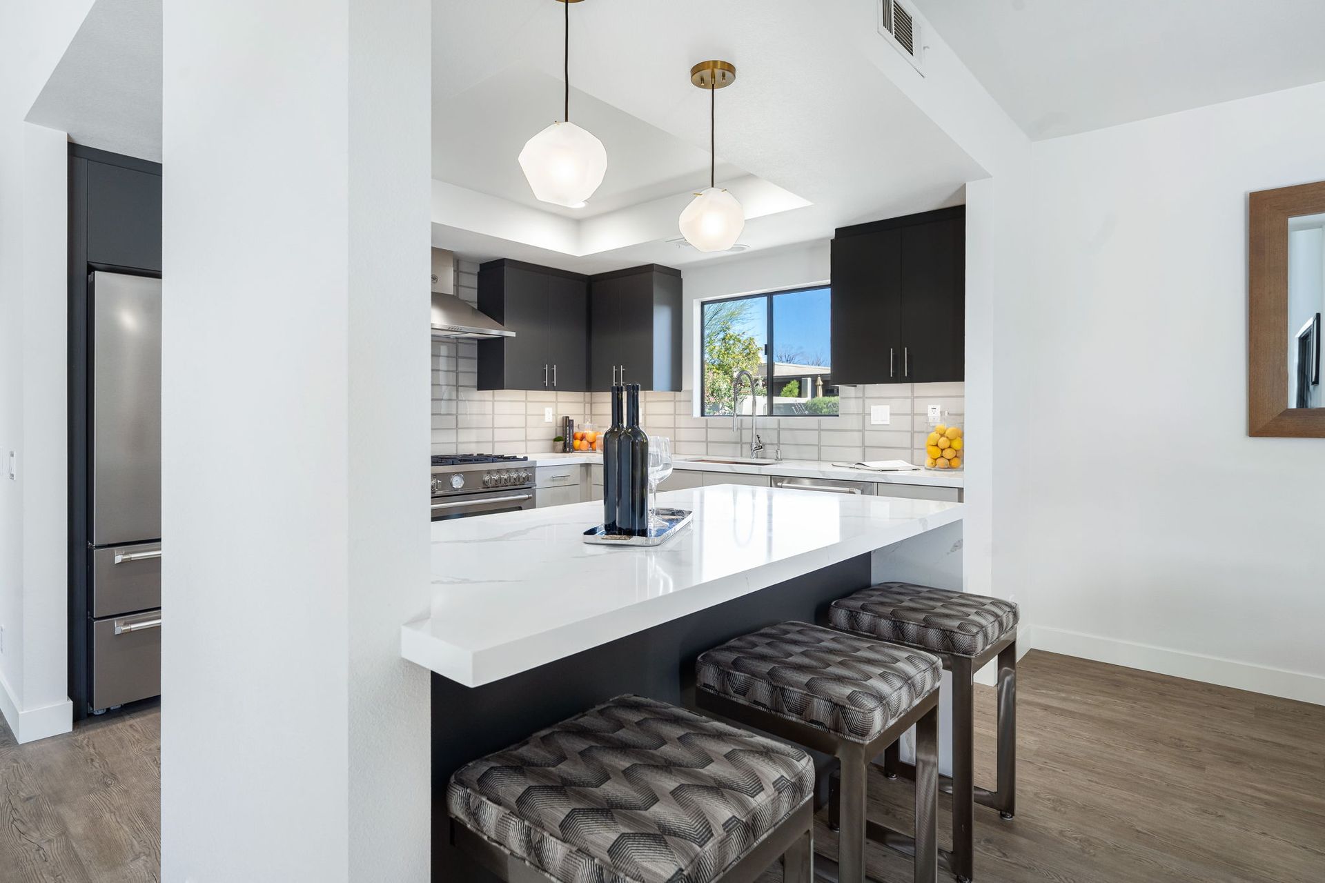 A kitchen with a bar and stools and a bottle of wine on the counter.