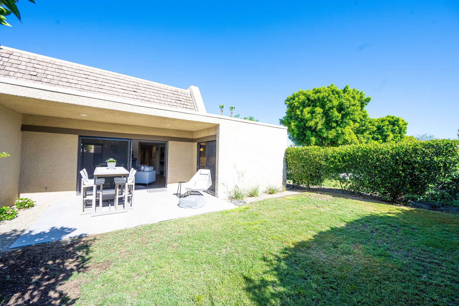 A house with a patio and a table and chairs in the backyard.