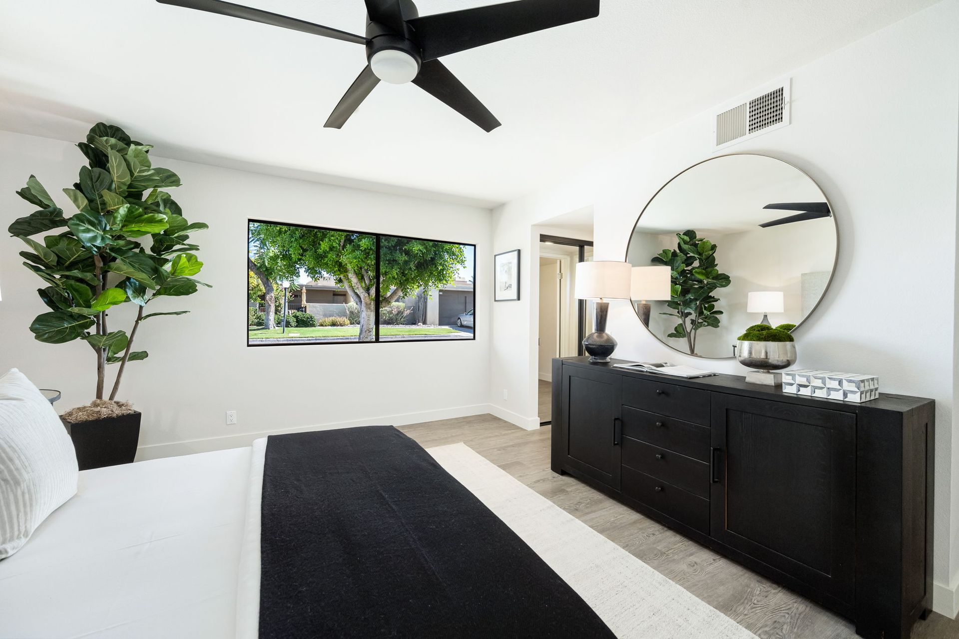 A bedroom with a bed , dresser , mirror and ceiling fan.