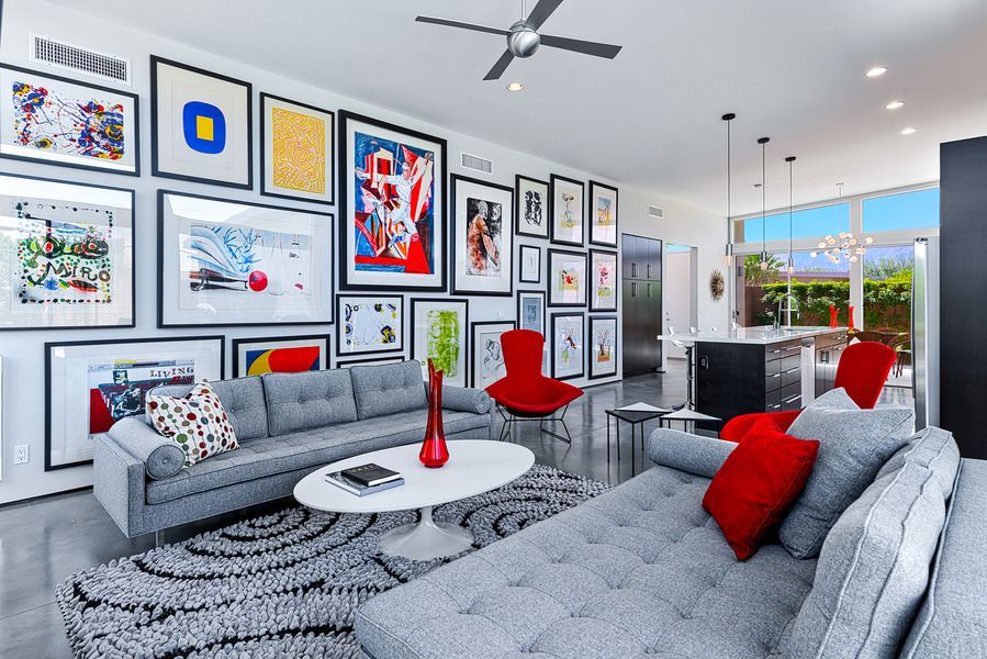 Living room with a gallery wall, grey couches, and red accents.