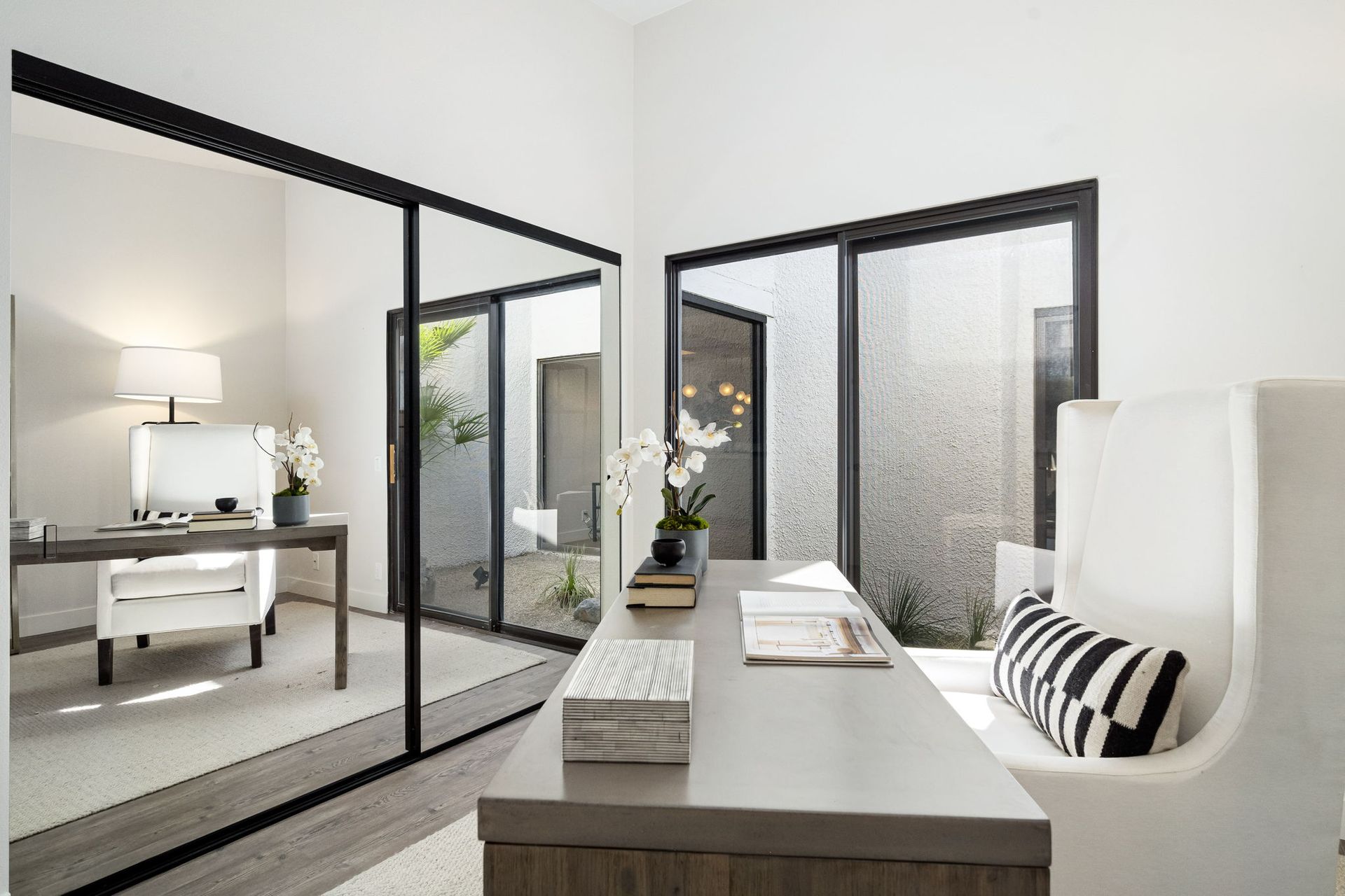 A home office with a desk , chair , and sliding glass doors.