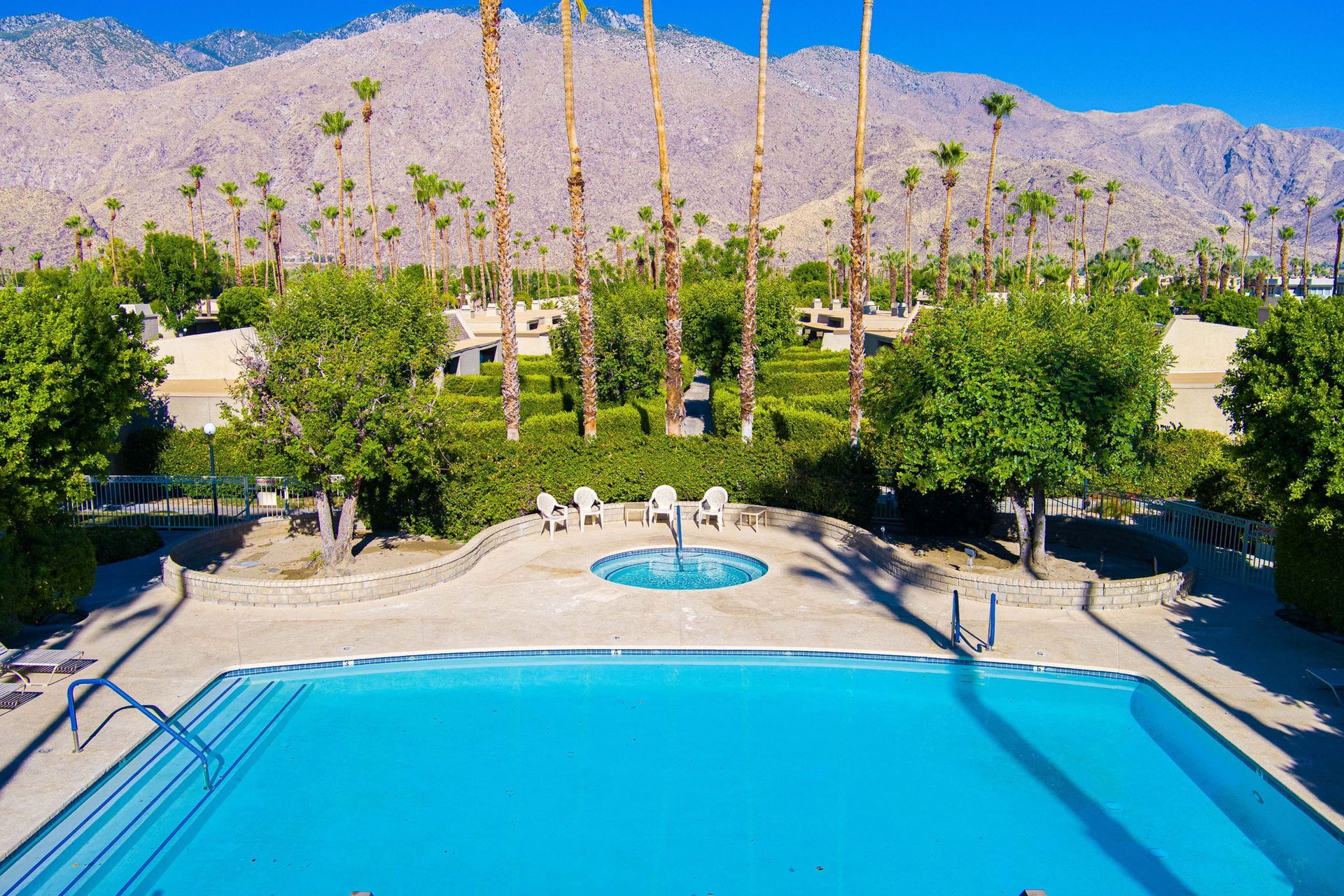 An aerial view of a large swimming pool with mountains in the background