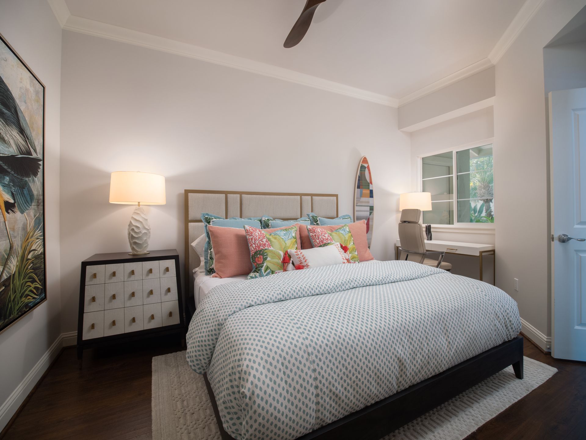 A bedroom with a bed , nightstand , lamps and a ceiling fan.