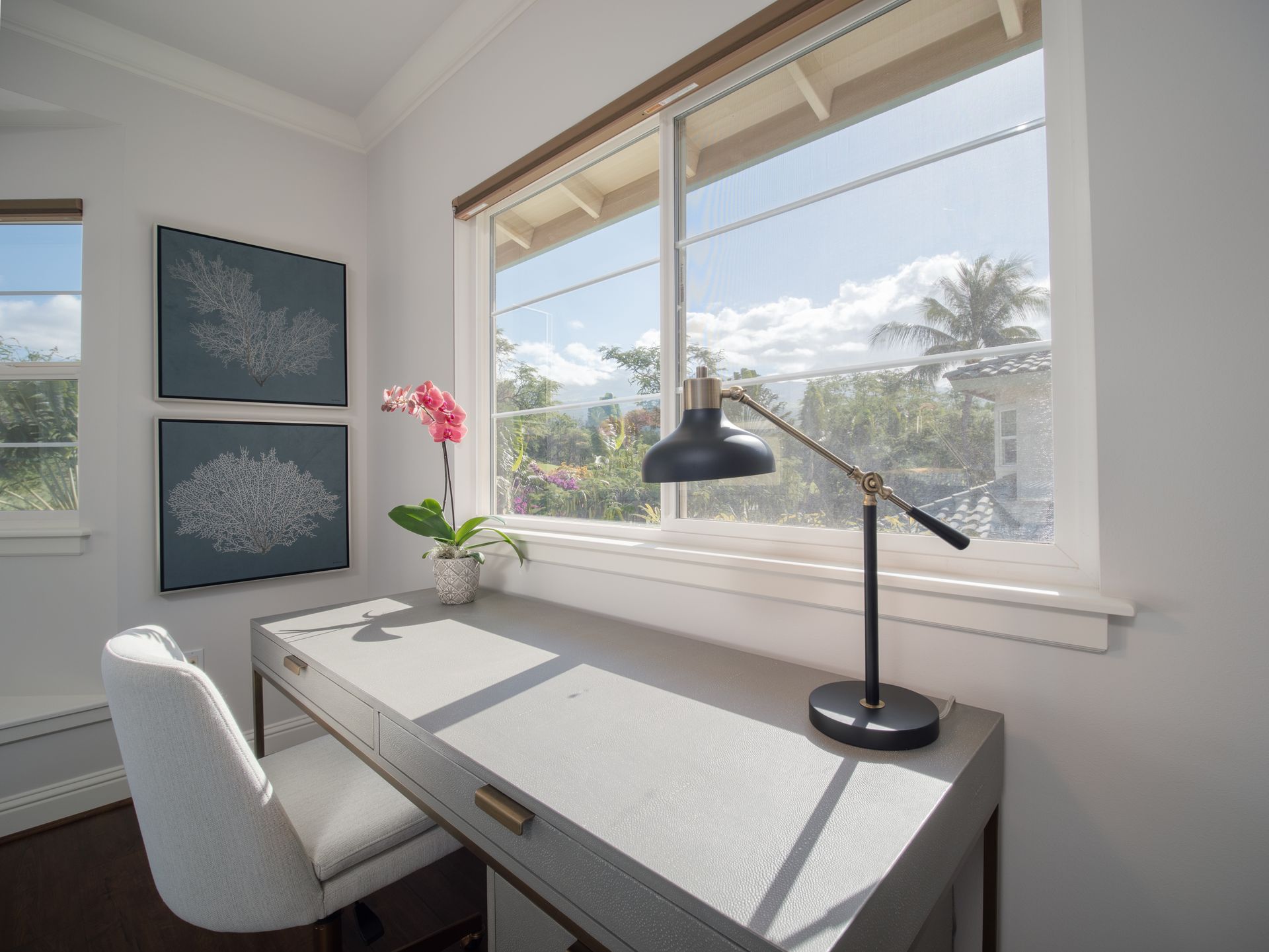 A desk with a lamp and a chair in front of a window.