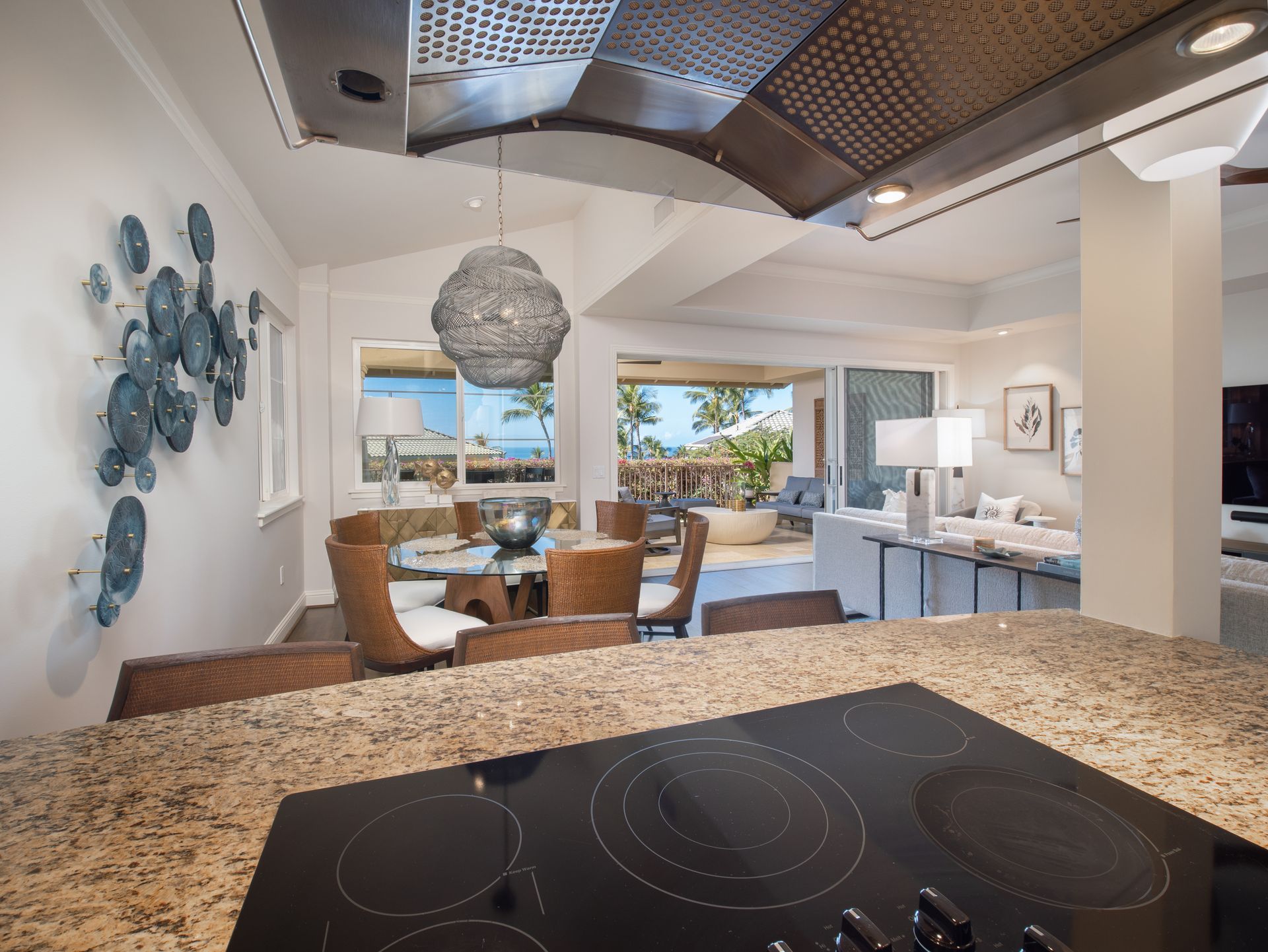 A kitchen with a stove top oven and a dining room in the background