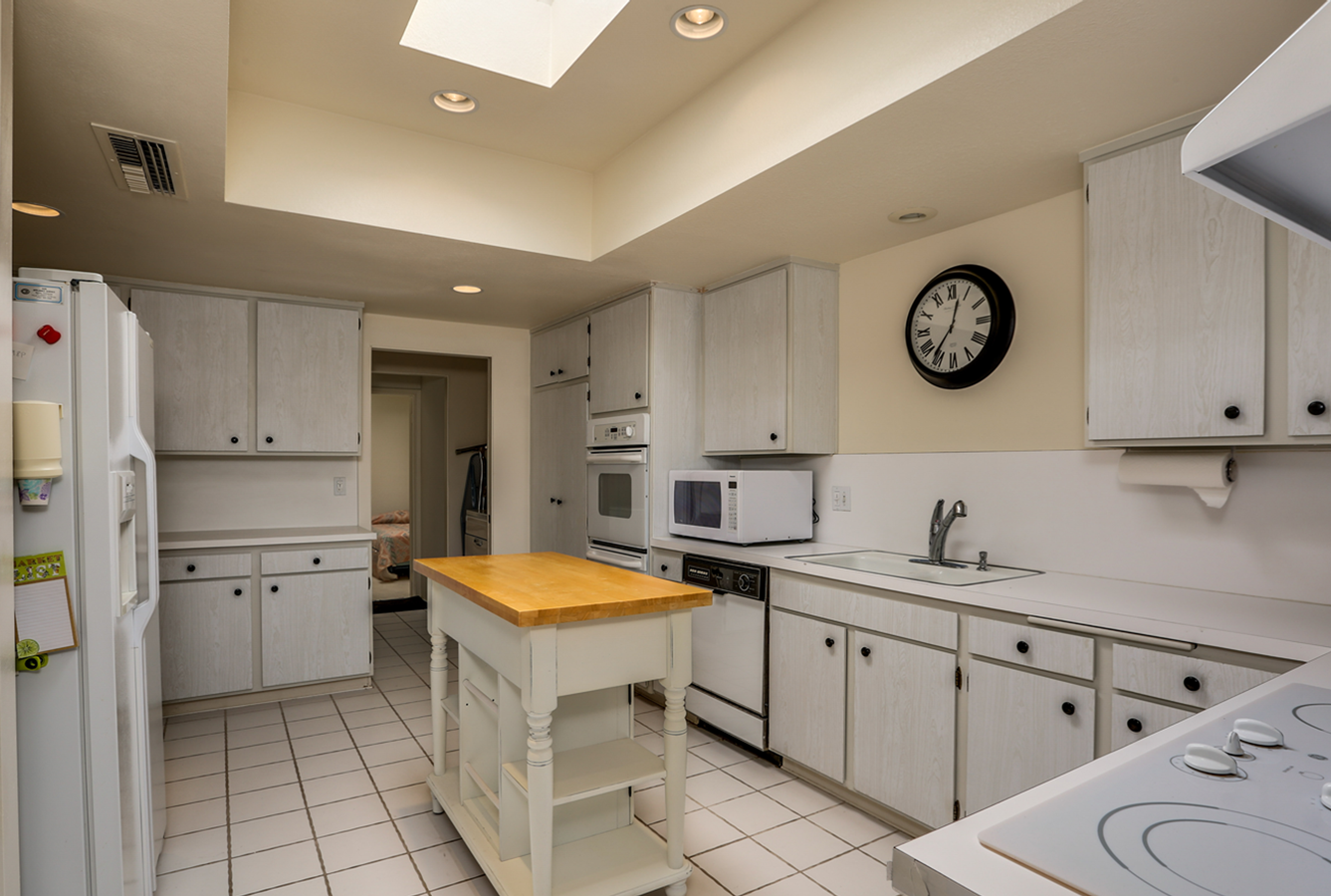 A kitchen with white cabinets and a clock on the wall