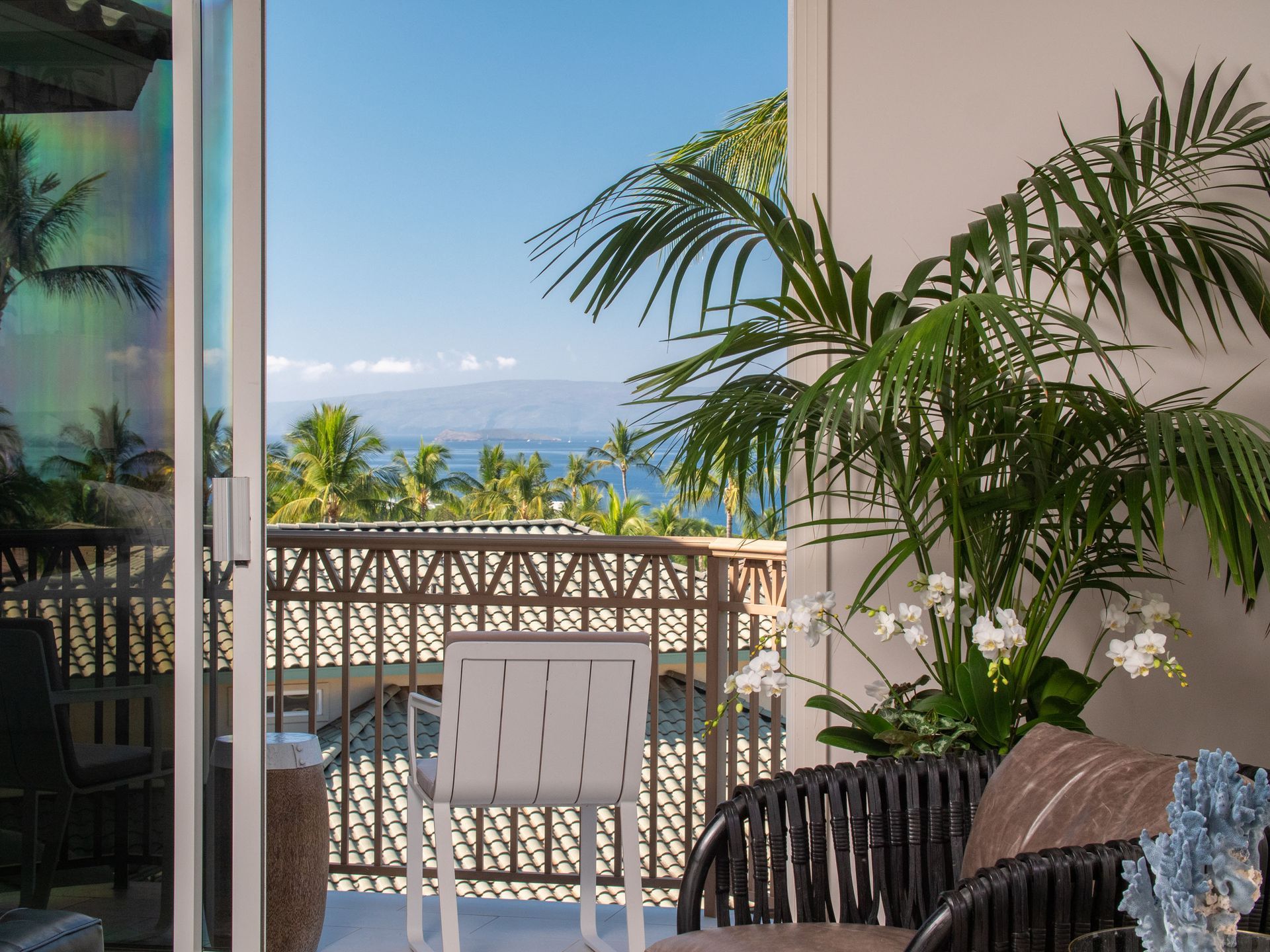 A balcony with a view of the ocean and palm trees