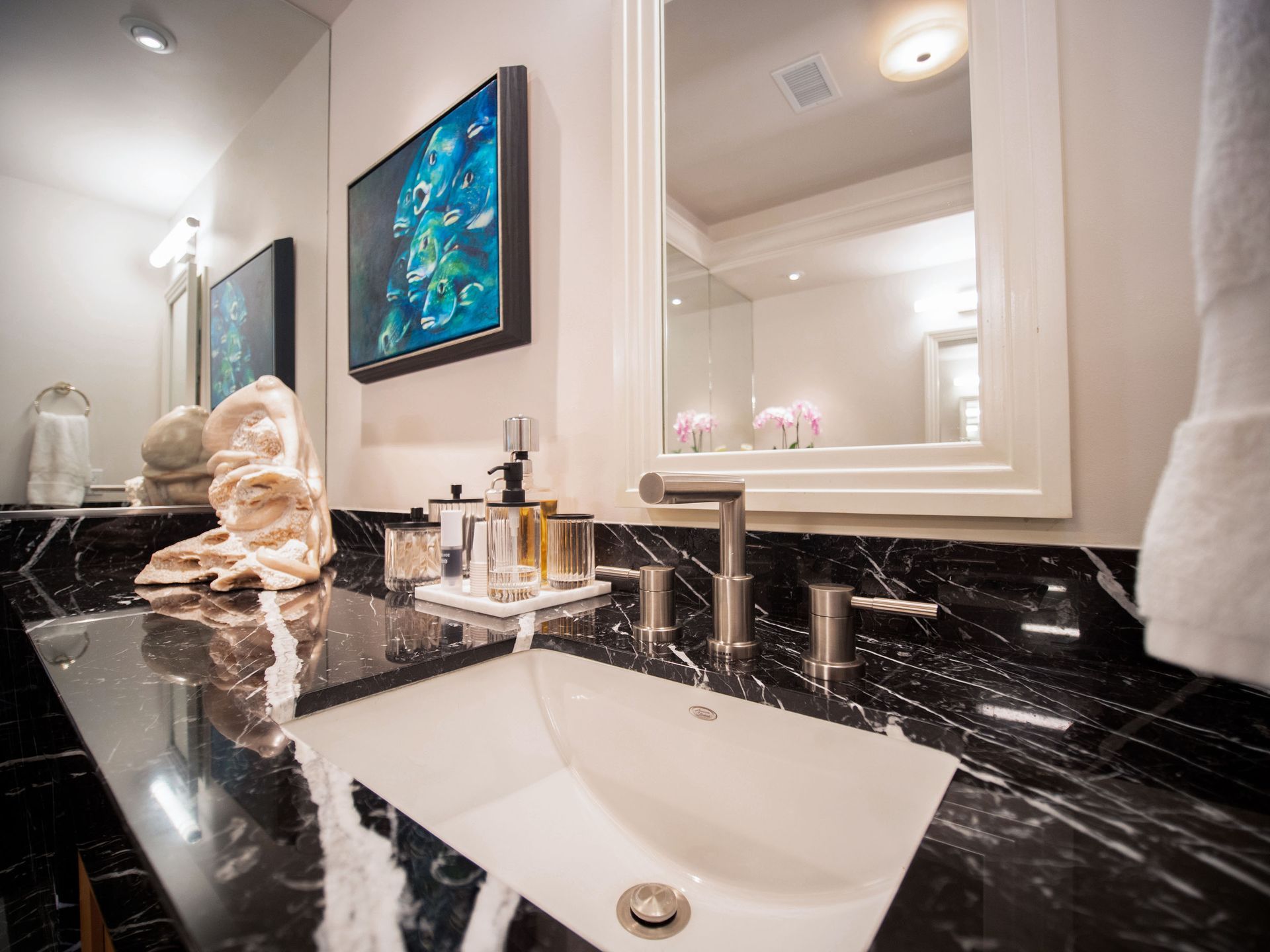 A bathroom with a sink , mirror , and towels.