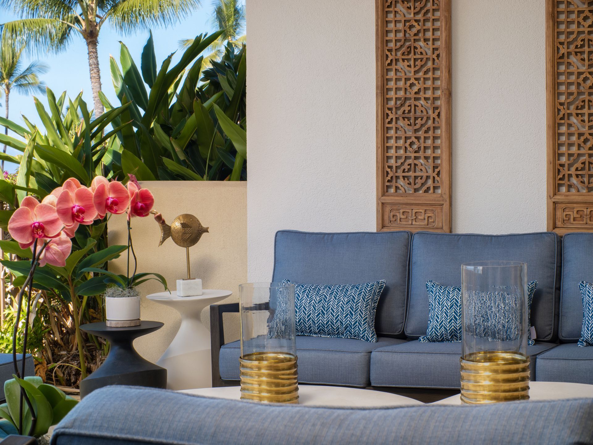 A living room with a blue couch and pink orchids