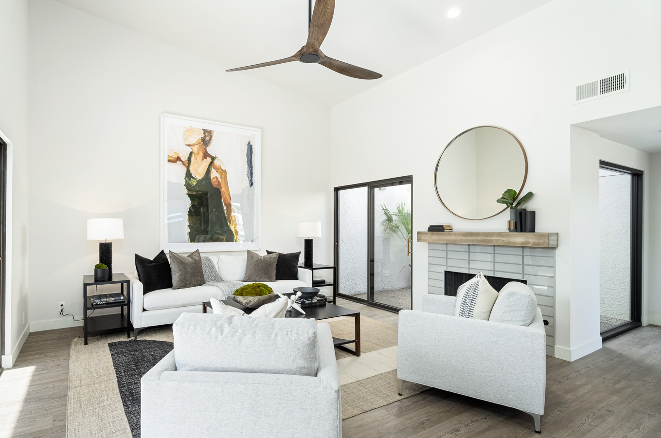 A living room with white furniture and a ceiling fan.